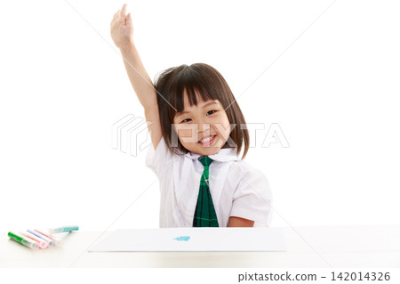 A little Asian kindergarten girl smiles happily at the camera against a white background. 142014326