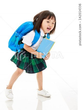 Happy primary school student wearing blue backpack and holding book for school Happy primary school student wearing blue backpack and holding book for school 142014336