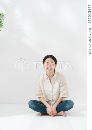 A smiling woman sitting on the floor with her legs crossed. A smiling woman sitting on the floor with her legs crossed. 142015455