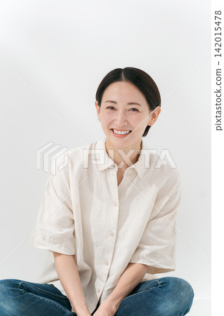 A smiling woman sitting on the floor with her legs crossed. A smiling woman sitting on the floor with her legs crossed. 142015478