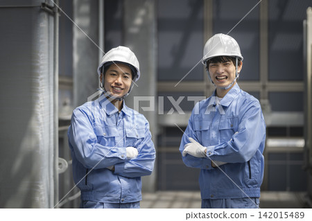 Two young workers smiling and looking at the camera Two young workers smiling and looking at the camera 142015489