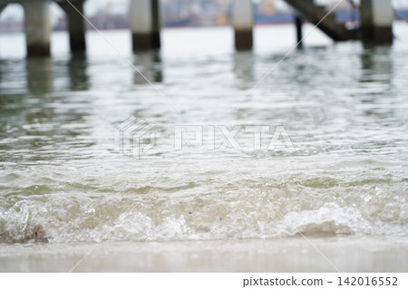 Gentle Waves on Sandy Shoreline Near Pier Structure 142016552