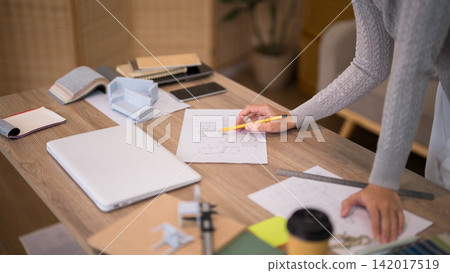 Asian furniture designer sketching technical drawing with yellow pencil on wooden workspace in home office with copy space Asian furniture designer sketching technical drawing with yellow pencil on wooden workspace in home office with copy space 142017519