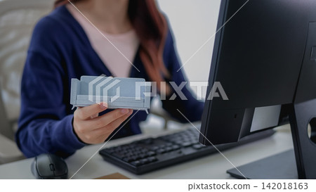 Young Asian furniture designer presenting material swatch palette at modern home office desk with computer 142018163