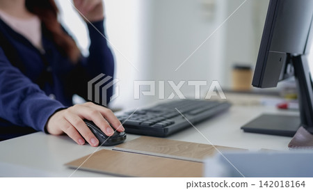 Asian woman furniture designer using computer mouse while working at modern office desk with copy space Asian woman furniture designer using computer mouse while working at modern office desk with copy space 142018164