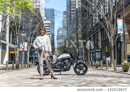 在丸之內，一位女商人站在一輛大型美式摩托車旁。 142018637