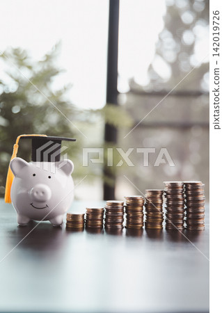 Piggy bank wearing a graduation cap beside rising coin stacks, representing education savings, tuition funding, financial growth, college preparation, academic ambition, and future achievement. Piggy bank wearing a graduation cap beside rising coin stacks, representing education savings, tuition funding, financial growth, college preparation, academic ambition, and future achievement. 142019726