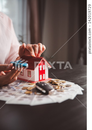 Person points toward a white car, rising coin stacks, and red roof house, representing savings strategy, loan planning, property purchase, vehicle financing, wealth growth, Person points toward a white car, rising coin stacks, and red roof house, representing savings strategy, loan planning, property purchase, vehicle financing, wealth growth, 142019729