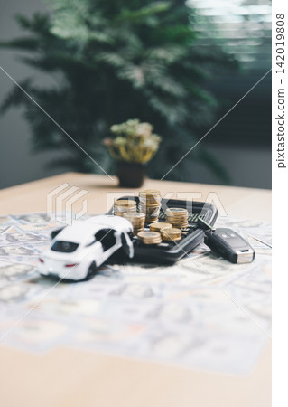 White toy car, calculator, coins, and car key on dollar bills, representing car finance calculation, auto loan budgeting, and total vehicle ownership cost. White toy car, calculator, coins, and car key on dollar bills, representing car finance calculation, auto loan budgeting, and total vehicle ownership cost. 142019808