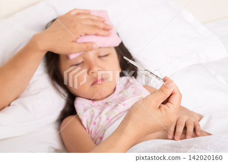 A sick Asian girl with a fever is having her temperature taken. 142020160