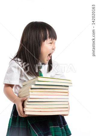 Tired little student carrying a heavy stack of textbooks looking exhausted in studio. Tired little student carrying a heavy stack of textbooks looking exhausted in studio. 142020163