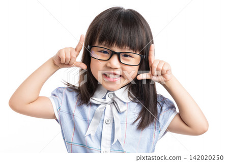 Funny little girl with glasses making a playful face towards the camera in studio. Funny little girl with glasses making a playful face towards the camera in studio. 142020250