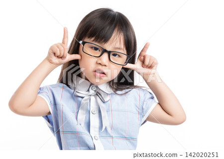 Funny little girl with glasses making a playful face towards the camera in studio. Funny little girl with glasses making a playful face towards the camera in studio. 142020251