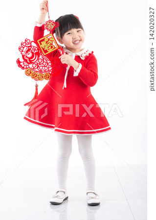A full length portrait of an Asian girl standing and holding two red Chinese New Year decorations in a white studio. A full length portrait of an Asian girl standing and holding two red Chinese New Year decorations in a white studio. 142020327