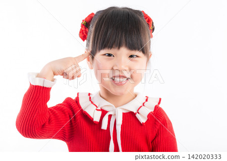 Cute Asian preschool girl in red sweater pointing at her ears with fingers smiling at camera. Cute Asian preschool girl in red sweater pointing at her ears with fingers smiling at camera. 142020333