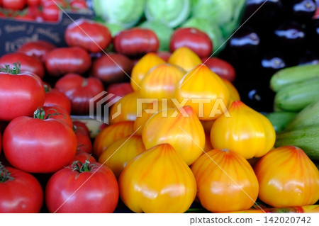 Fresh yellow, red and pink tomatoes displayed at local farmers market, colorful heirloom produce, seasonal farm harvest for healthy cooking and everyday grocery shopping Fresh yellow, red and pink tomatoes displayed at local farmers market, colorful heirloom produce, seasonal farm harvest for healthy cooking and everyday grocery shopping 142020742