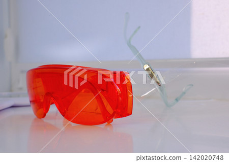 Orange dental safety glasses for eye protection during professional treatment in modern dental clinic close up medical protective equipment photography Orange dental safety glasses for eye protection during professional treatment in modern dental clinic close up medical protective equipment photography 142020748