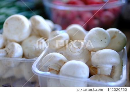 Fresh white button mushrooms in plastic containers at local farmers market, seasonal edible mushrooms for healthy cooking, natural farm produce and grocery shopping Fresh white button mushrooms in plastic containers at local farmers market, seasonal edible mushrooms for healthy cooking, natural farm produce and grocery shopping 142020760