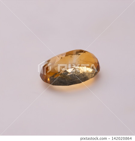 Faceted Yellow Brown Gemstone Resting on Neutral Pale Background with Soft Studio Lighting Faceted Yellow Brown Gemstone Resting on Neutral Pale Background with Soft Studio Lighting 142020864