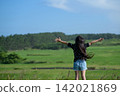 A girl's back view as she spreads her arms wide in a grassland in Tohoku, experiencing a sense of liberation | An image of a free and positive childhood. 142021869