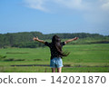 A girl's back view as she spreads her arms wide in a grassland in Tohoku, experiencing a sense of liberation | A medium-length shot of a free and positive childhood. 142021870