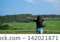 A girl's back view, arms outstretched in a vast grassland in Tohoku | A wide shot conveys a sense of freedom. 142021871