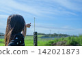 A girl's back as she points to a dragonfly perched on a fence in a pasture in Tohoku | A snapshot of a curious childhood. 142021873