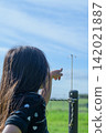 A girl's back view as she points to a dragonfly perched on a fence in a pasture in Tohoku | Vertical close-up stock photo for social media ads 142021887