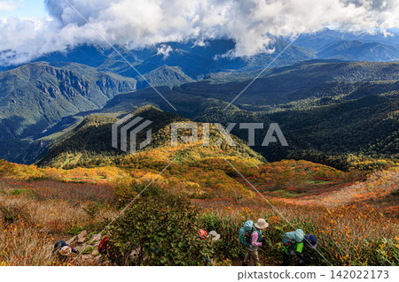 Hikers enjoy the spectacular autumn scenery as they make their way to the summit of Mt. Kurodake in the Daisetsuzan Mountains in early autumn. Hikers enjoy the spectacular autumn scenery as they make their way to the summit of Mt. Kurodake in the Daisetsuzan Mountains in early autumn. 142022173