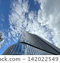 Towering skyscrapers and white clouds spreading across the blue sky. 142022549