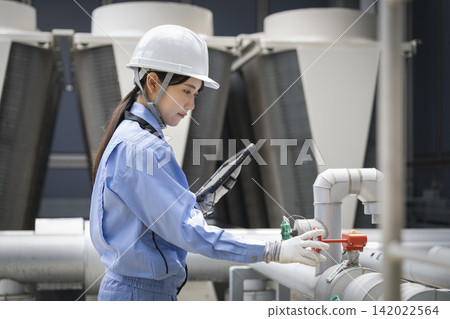 A young female worker inspecting the building's equipment. A young female worker inspecting the building's equipment. 142022564