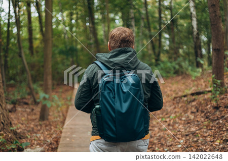 Blonde young man wearing backpack standing on autumn forest trail, hiking alone. Freedom and active lifestyle concept. High quality photo, rear wiev Blonde young man wearing backpack standing on autumn forest trail, hiking alone. Freedom and active lifestyle concept. High quality photo, rear wiev 142022648