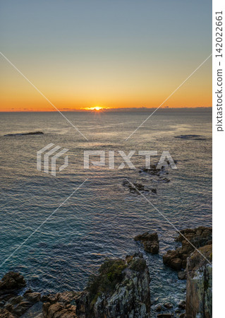 Aerial view of a golden sunrise over the ocean, with warm morning light illuminating the coastline and surrounding landscape at Diamond Head. Aerial view of a golden sunrise over the ocean, with warm morning light illuminating the coastline and surrounding landscape at Diamond Head. 142022661