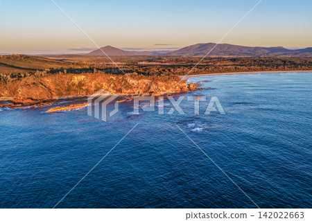 Aerial view of Diamond Head Beach and headland surrounded by ocean and coastal landscape beneath soft pastel morning light at Diamond Head. Aerial view of Diamond Head Beach and headland surrounded by ocean and coastal landscape beneath soft pastel morning light at Diamond Head. 142022663