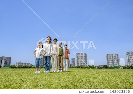 A three-generation family lined up on the riverbank, all smiling. 142023396