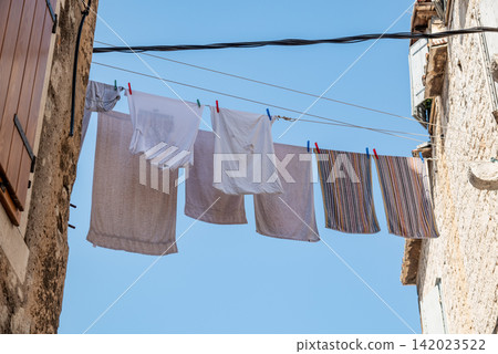 A serene scene of clothes drying on a weathered clothesline against a clear A serene scene of clothes drying on a weathered clothesline against a clear 142023522
