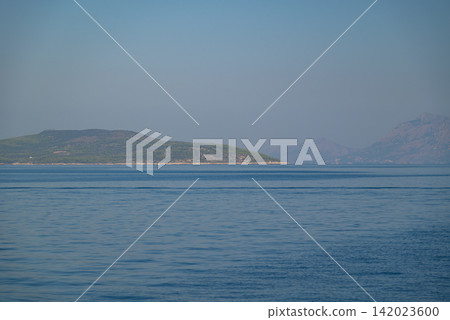A serene seascape with a large verdant island rising from deep blue water A serene seascape with a large verdant island rising from deep blue water 142023600