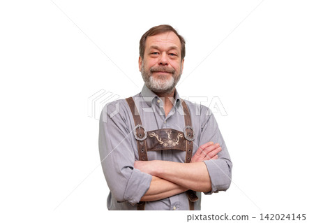Smiling mature man in traditional Bavarian suspenders standing with crossed arms Smiling mature man in traditional Bavarian suspenders standing with crossed arms 142024145