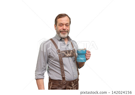 Smiling mature man in lederhosen holding blue mug and posing Smiling mature man in lederhosen holding blue mug and posing 142024156
