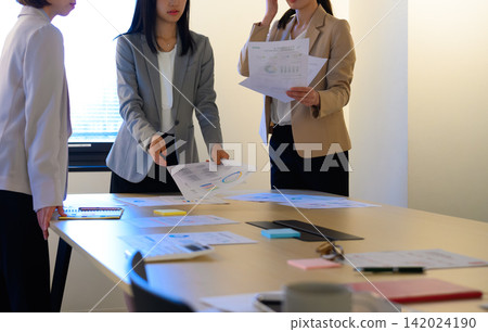 會議室裡，幾位女士正在開會期間審閱文件。 142024190
