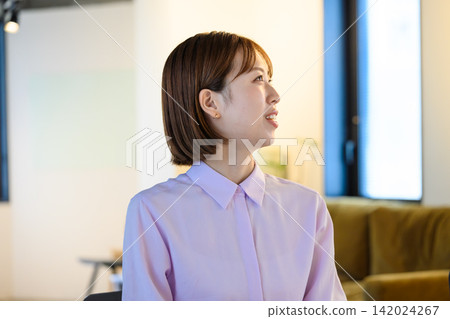 一位女士面帶微笑，在辦公室與人交談，看起來很享受。 142024267