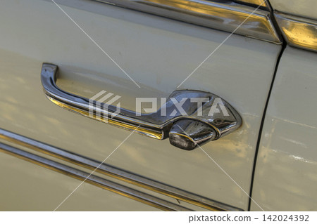 Tavernes Blanques, Spain - June 14, 2026. Close up of vintage chrome door handle and metallic side trim on classic Seat sedan parked on city street in sunlight Tavernes Blanques, Spain - June 14, 2026. Close up of vintage chrome door handle and metallic side trim on classic Seat sedan parked on city street in sunlight 142024392