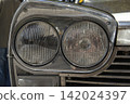 Tavernes Blanques, Spain - June 14, 2026. Close up view of dual round headlights in chrome housing on classic Seat automobile 142024397
