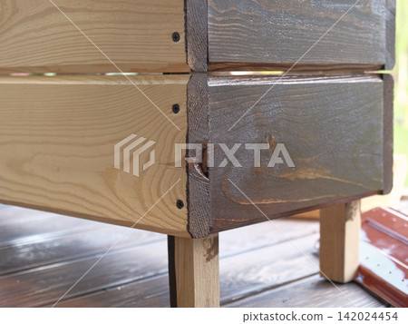 Brown oil for protection of wood by staining. Painting fence for protecting and pests. Woodworker applying finish to pine board box. Repairman varnishing with brush wooden fencing wall plank surface. Brown oil for protection of wood by staining. Painting fence for protecting and pests. Woodworker applying finish to pine board box. Repairman varnishing with brush wooden fencing wall plank surface. 142024454