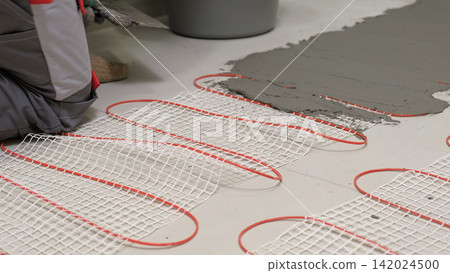 Electric Heating Mat Installing in the Tile Adhesive. Underfloor Dual Core Fiberglass Mesh Mat. Warm Floor Heating System. Warming. Worker Applying Concrete Mortar for Warm Floor. Renovation work. 4K Electric Heating Mat Installing in the Tile Adhesive. Underfloor Dual Core Fiberglass Mesh Mat. Warm Floor Heating System. Warming. Worker Applying Concrete Mortar for Warm Floor. Renovation work. 4K 142024500