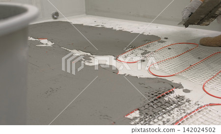 Electric Heating Mat Installing in the Tile Adhesive. Underfloor Dual Core Fiberglass Mesh Mat. Warm Floor Heating System. Warming. Worker Applying Concrete Mortar for Warm Floor. Renovation work. 4K Electric Heating Mat Installing in the Tile Adhesive. Underfloor Dual Core Fiberglass Mesh Mat. Warm Floor Heating System. Warming. Worker Applying Concrete Mortar for Warm Floor. Renovation work. 4K 142024502