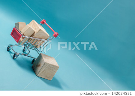 Mini trolley loaded with wooden blocks on a blue background representing online shopping and delivery. High Quality Photo Mini trolley loaded with wooden blocks on a blue background representing online shopping and delivery. High Quality Photo 142024551