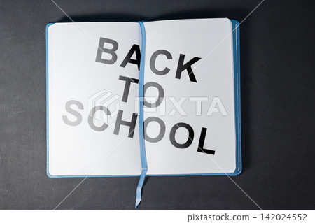 Top view of an open blue notebook with Back to School text on clean white pages over a dark wooden background. High Quality Photo Top view of an open blue notebook with Back to School text on clean white pages over a dark wooden background. High Quality Photo 142024552