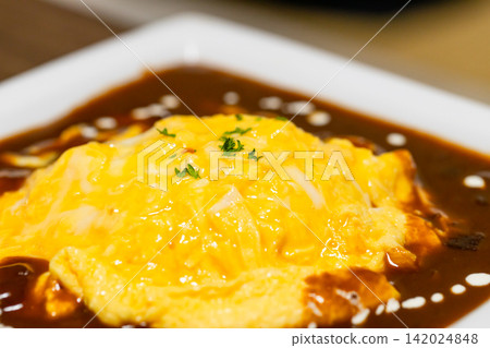 A creamy omelet rice topped with demi-glace sauce, decorated with parsley and cream. A creamy omelet rice topped with demi-glace sauce, decorated with parsley and cream. 142024848