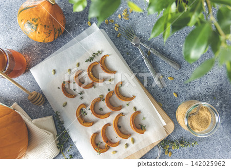 Autumn vegetarian food recipe. Baked mini pumpkin with herbs, and honey on a wooden board over grey table top view Autumn vegetarian food recipe. Baked mini pumpkin with herbs, and honey on a wooden board over grey table top view 142025962